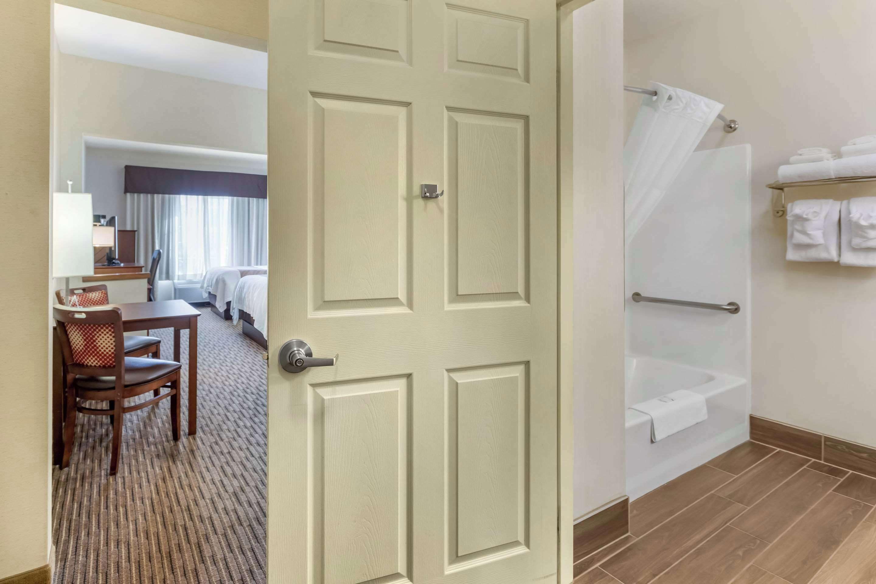 A hotel room with a bed, a desk with a chair, a bathroom with a bathtub, and a shower.