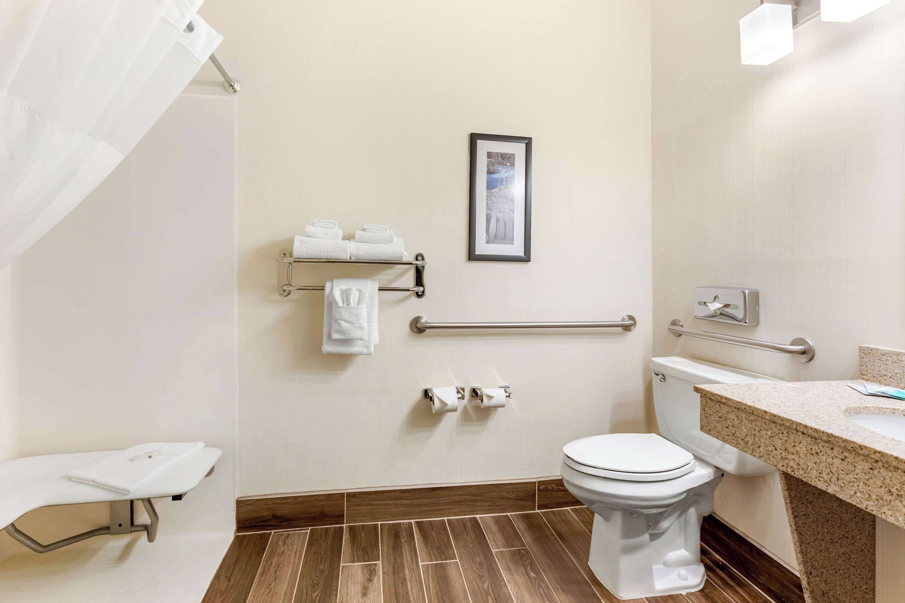 A bathroom with a toilet, a sink, a shower area, and a towel rack.