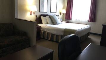 Quarto de hotel com uma cama, duas luminárias de cabeceira, uma escrivaninha e uma cadeira.