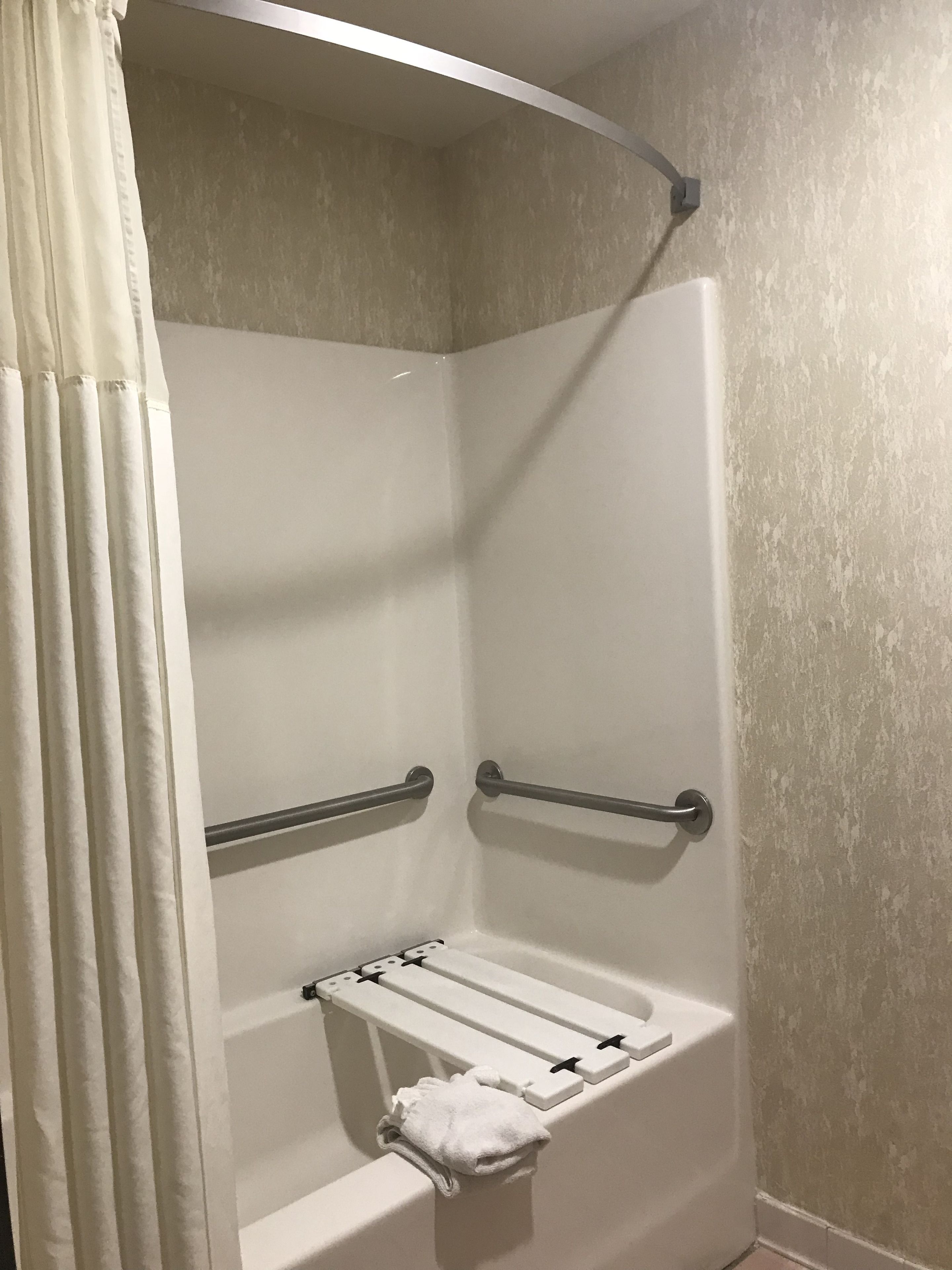 A shower with grab bars and a towel rack.