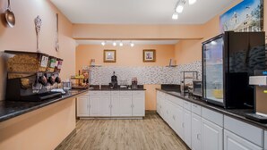 A modern kitchen with white cabinets, a black countertop, and a large refrigerator.
