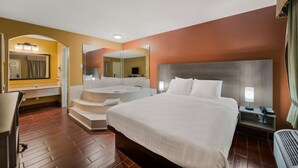 A hotel room with a large bed, a bathroom with a bathtub, a desk, and a chair.