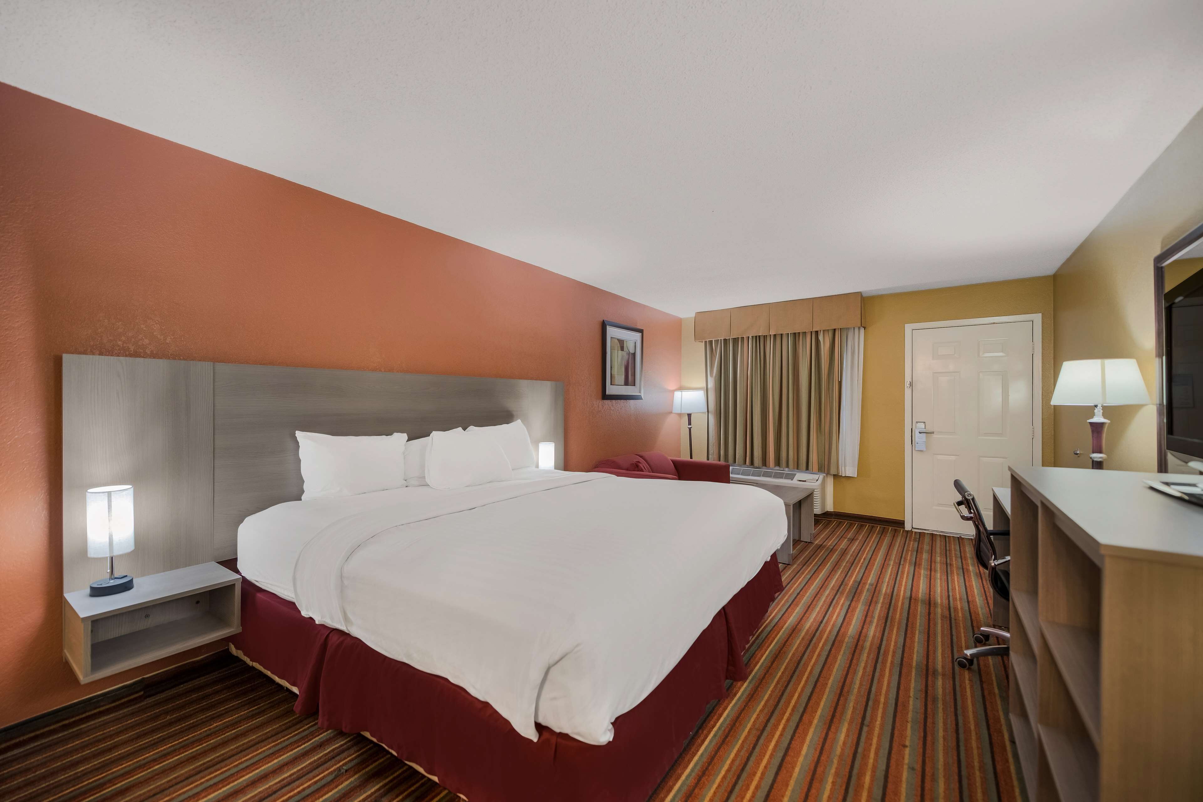 Een hotelkamer met een groot bed, nachtkastjes, een bureau, een stoel en een televisie.