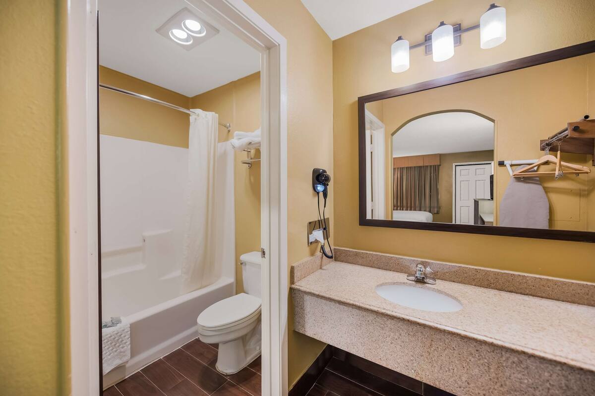 A bathroom with a bathtub, toilet, sink, and a mirror.