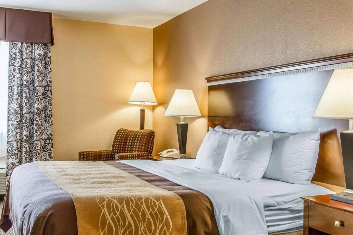 Une chambre d’hôtel avec un grand lit, deux lampes de chevet, une chaise et un téléphone.