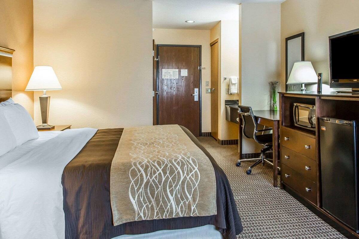 Une chambre d’hôtel équipée d’un lit, d’un bureau, d’une chaise, d’une télévision et d’un réfrigérateur.
