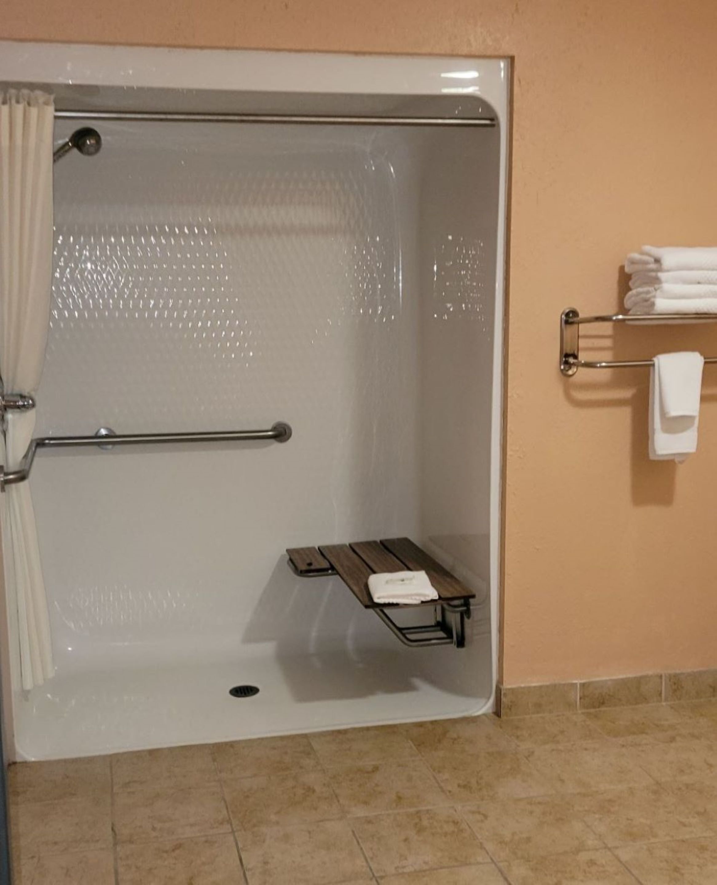 Baño con cabina de ducha, perchero y banco.
