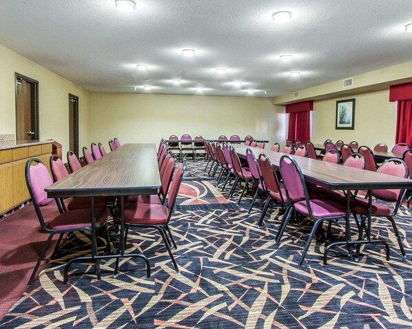 Un salón de conferencias con una larga mesa, varias sillas y piso alfombrado.