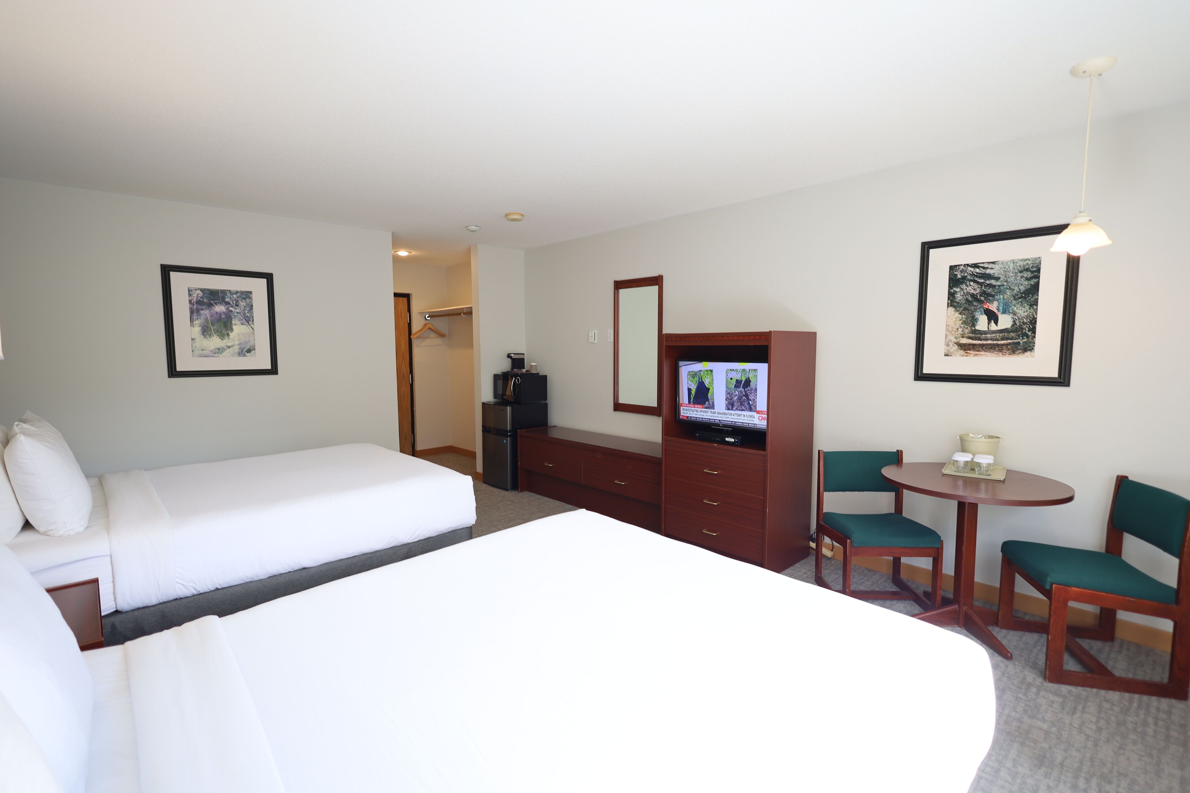 A hotel room with a bed, a desk, a television, and two chairs.