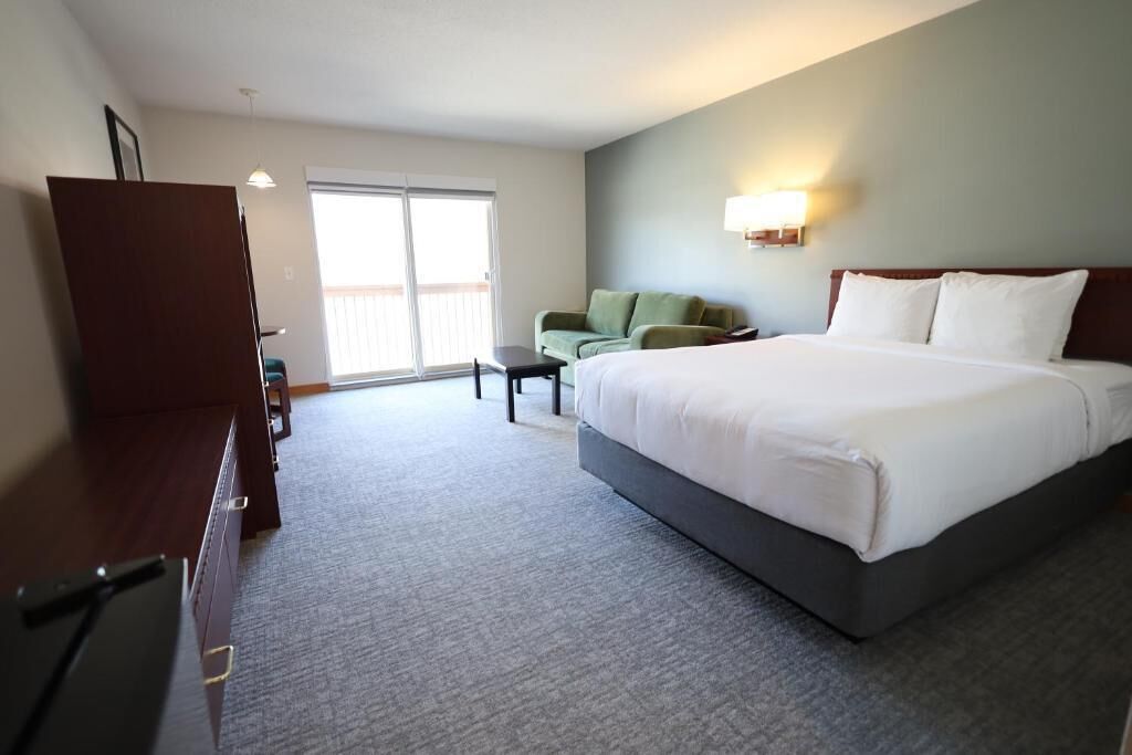 Une chambre d’hôtel avec un grand lit, un bureau, une chaise et un canapé. Il y a une fenêtre donnant sur l’extérieur.