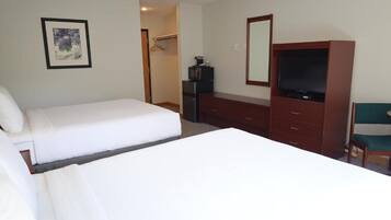 Ein Hotelzimmer mit einem Bett, einem Schminktisch, einem Fernseher und einem gerahmten Bild an der Wand.