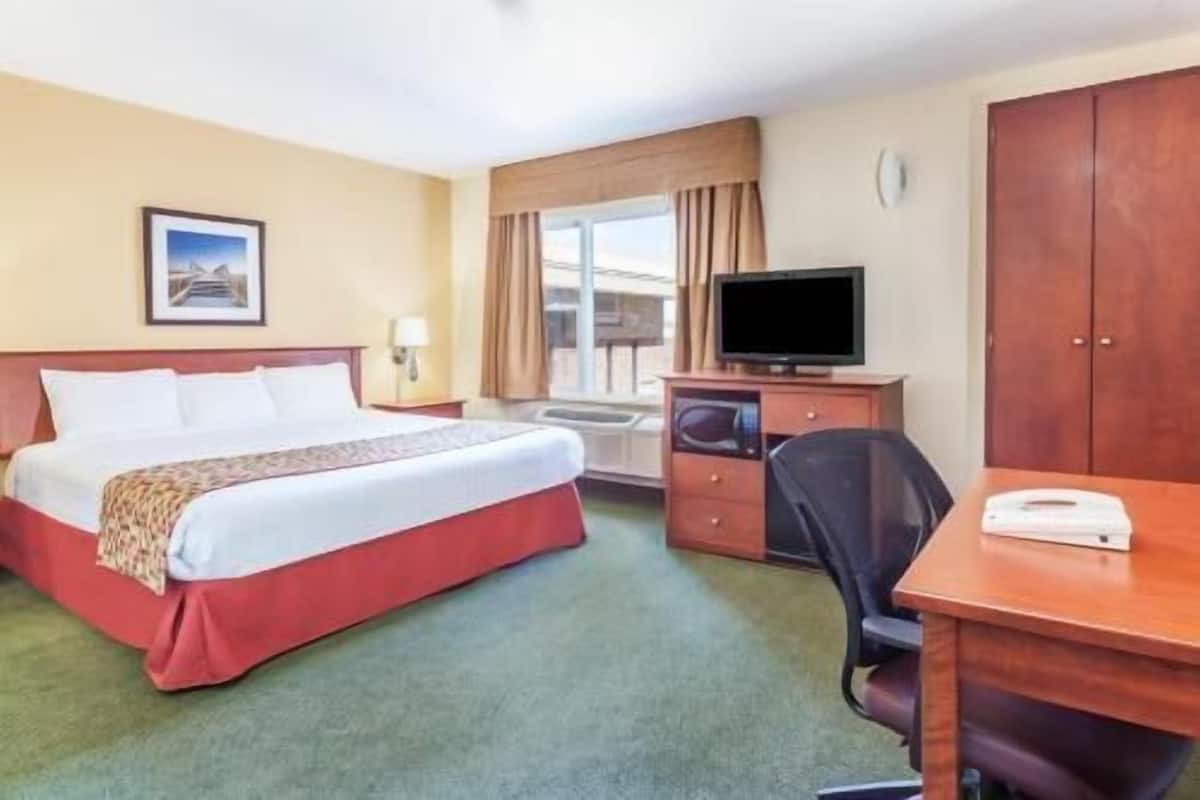 A hotel room with a bed, a desk, a television, and a wardrobe.