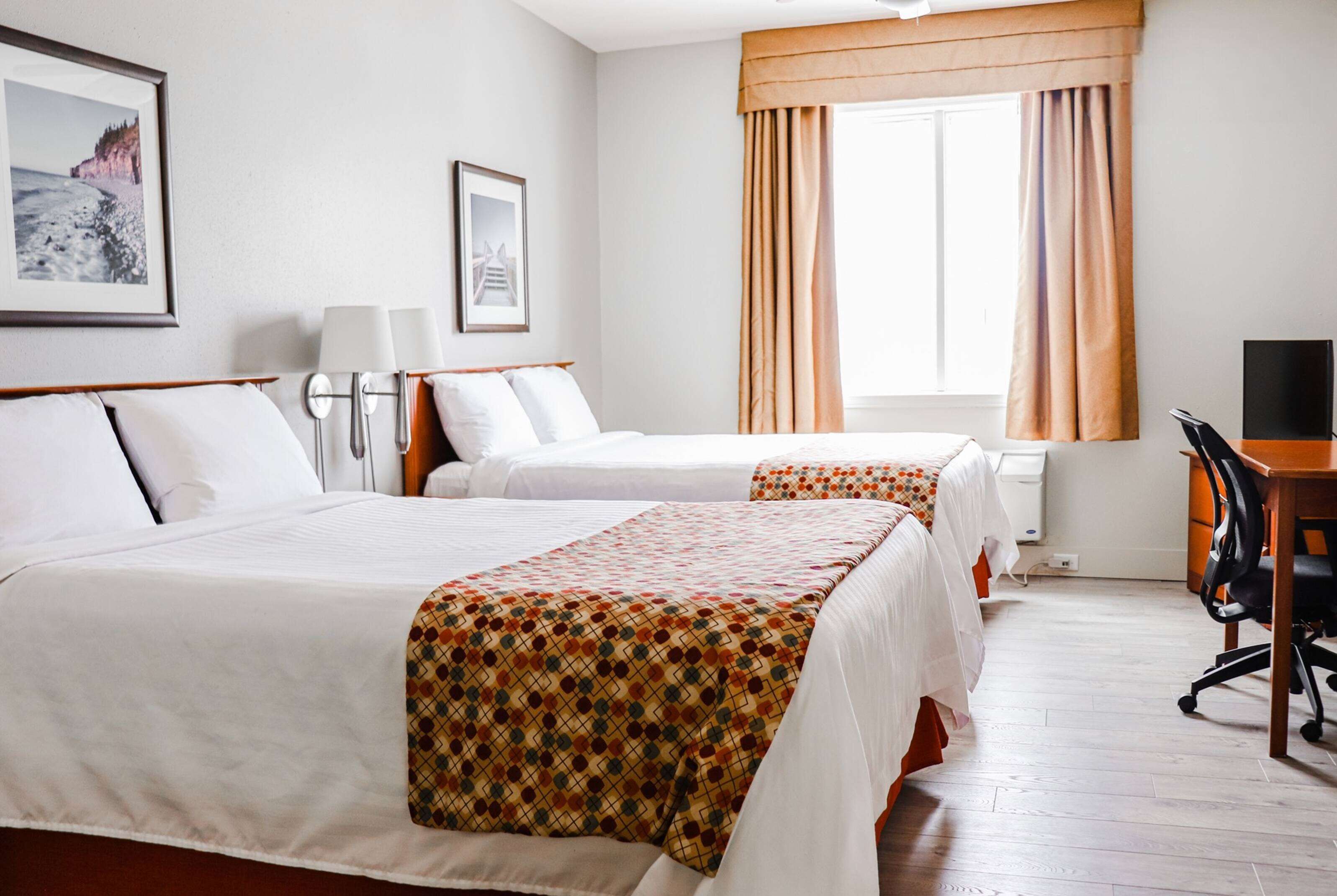 Une chambre d’hôtel avec deux lits, un bureau et une chaise.