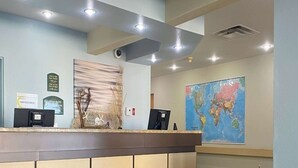 Zona de recepción con mostrador, un mapa mundial, una cámara de seguridad y un tablón de anuncios.