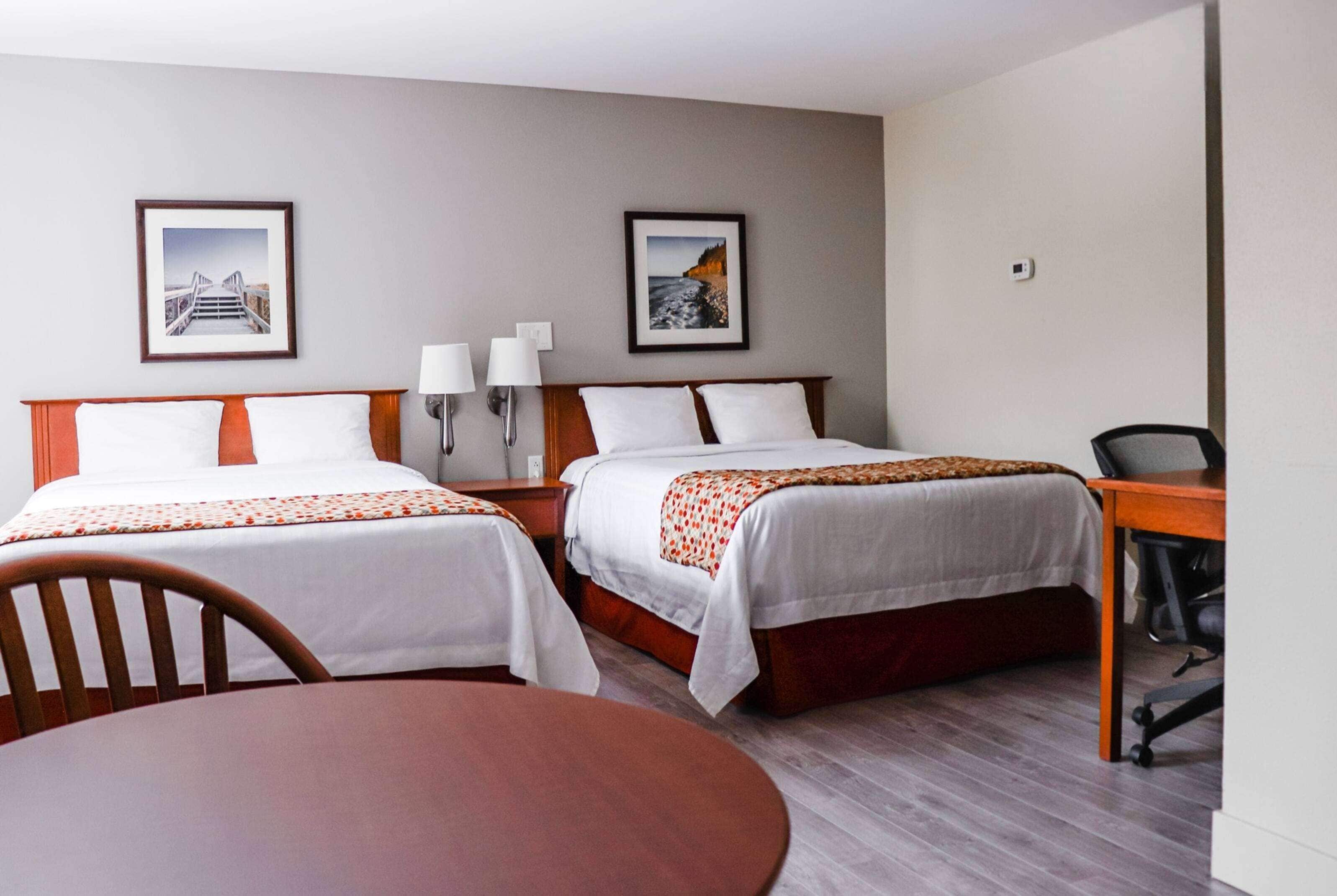 A hotel room with two beds, a desk, and a chair.