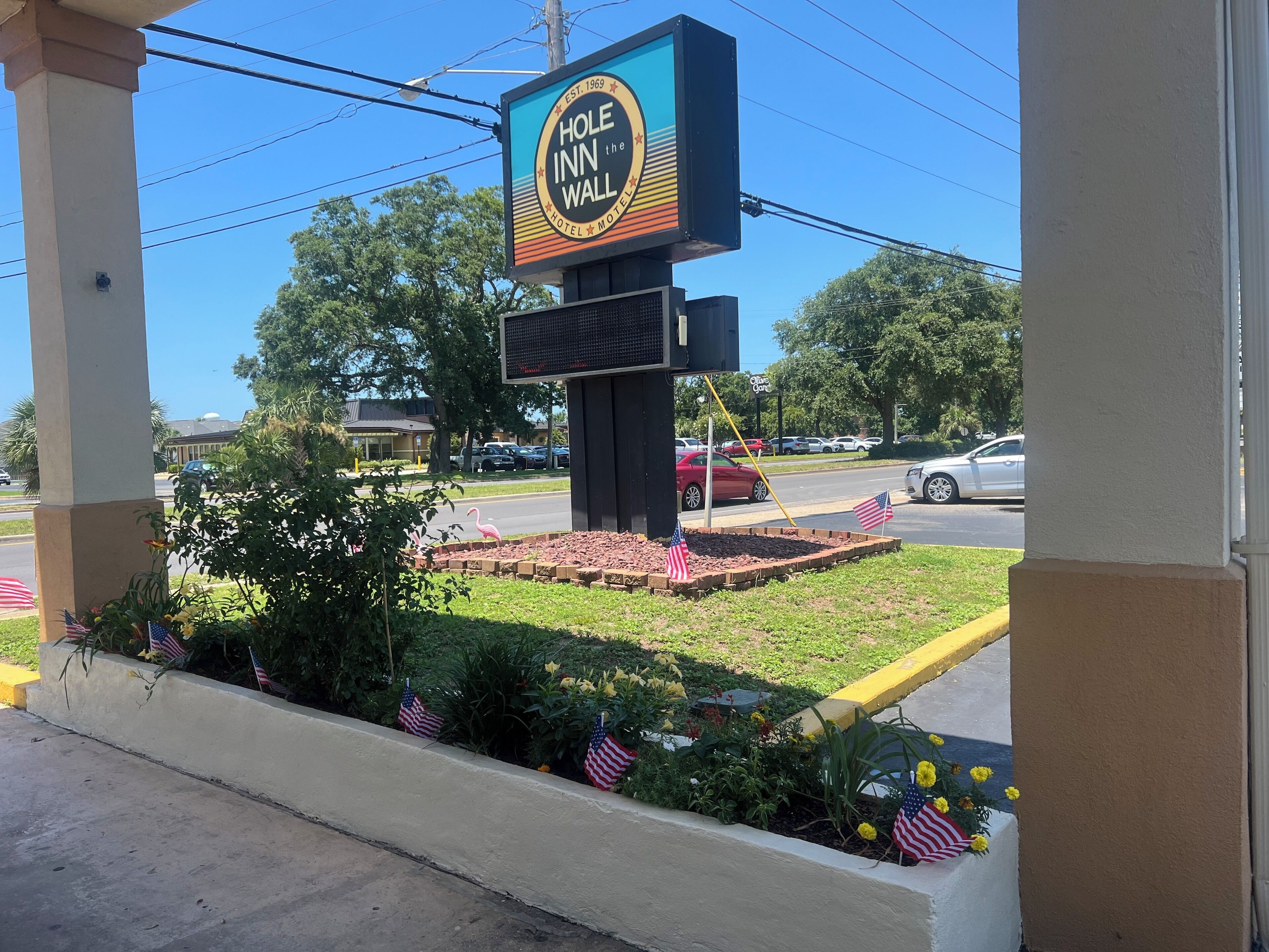 Letrero de motel con jardín de flores y banderas estadounidenses.