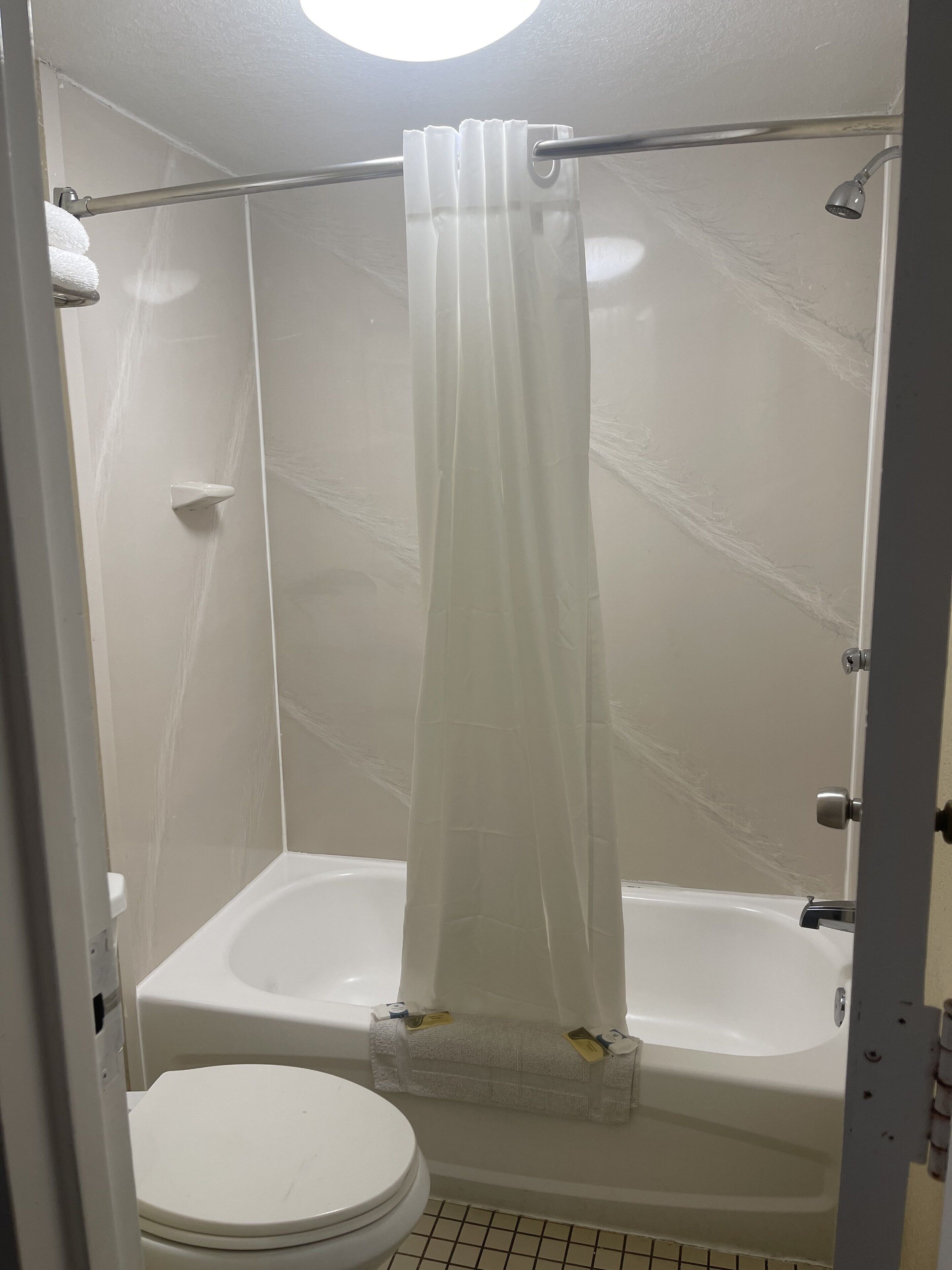 Een badkamer met bad, toilet en douchegordijn.