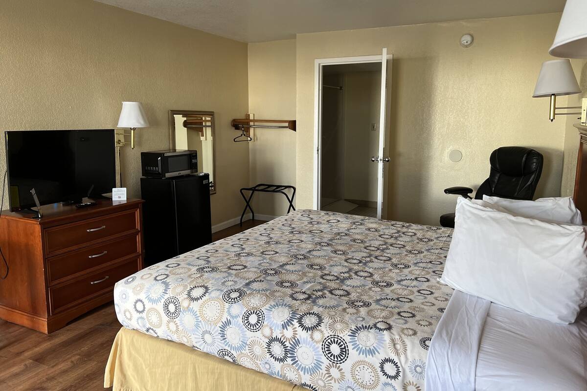 Ein Hotelzimmer mit einem Bett, einem Fernseher, einem Schreibtisch, einem Stuhl und einem Kleiderschrank.