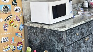 Zona de recepción de hotel con un microondas blanco en la encimera, un espejo grande encima y un cartel que dice “Relentless Pursuit of Perfection”.