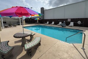 Relax by the pool surrounded by lounge chairs and a shaded area.