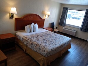 Cozy retreat with a neatly made bed, nightstand, and comfortable seating area.
