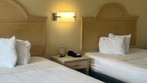 Habitación de hotel con dos camas, una mesita de noche con una lámpara y un teléfono.