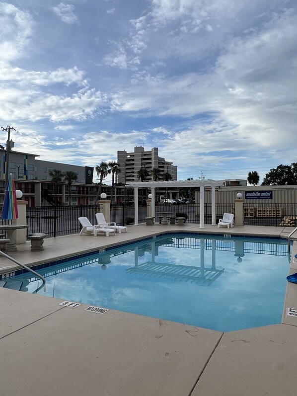 A swimming pool with lounge chairs, a sign for 'mobile mini', and a building in the background.