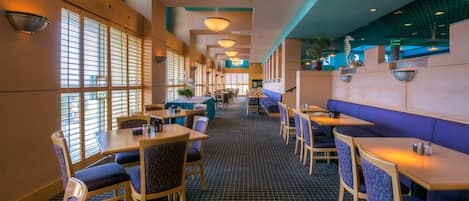 Un restaurant avec des banquettes et des tables, un sol à motifs et des luminaires suspendus.