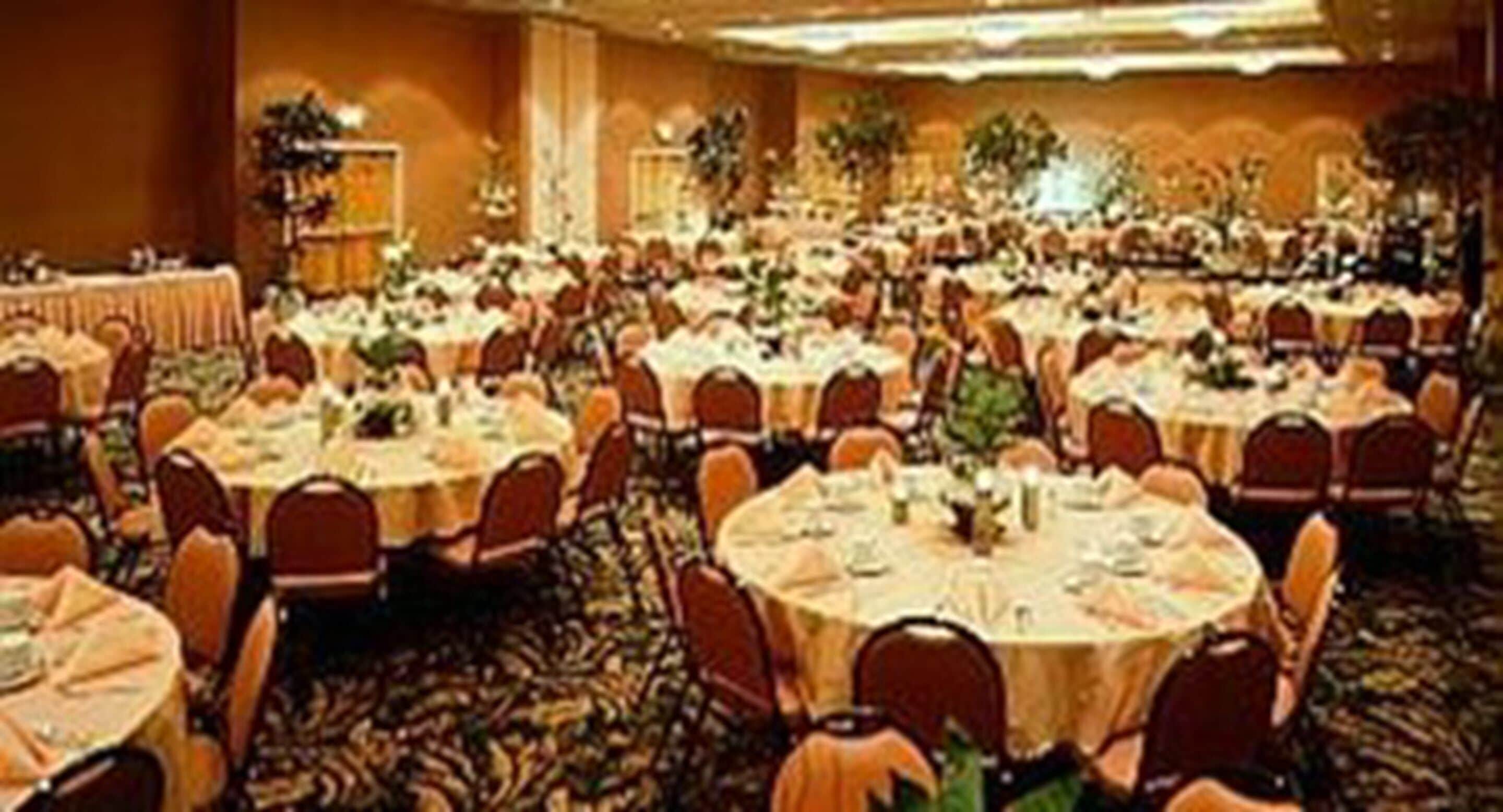 A banquet hall with round tables and chairs, arranged in rows.