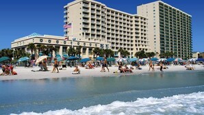 A beachfront hotel with multiple balconies, a pool, and beach umbrellas. - Ocean Drive Beach & Golf Resort (North Myrtle Beach)
