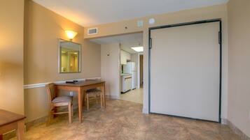 A hotel room with a dining area, a large mirror, a sliding door, and a view into the kitchen.