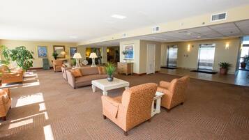 A spacious lobby with multiple seating areas, a reception desk, and a view of the elevators.
