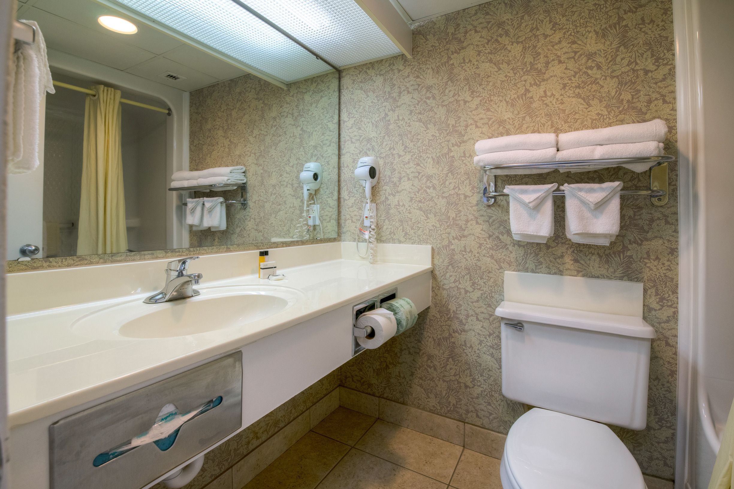 A bathroom with a sink, mirror, towel rack, toilet, and a shower curtain.