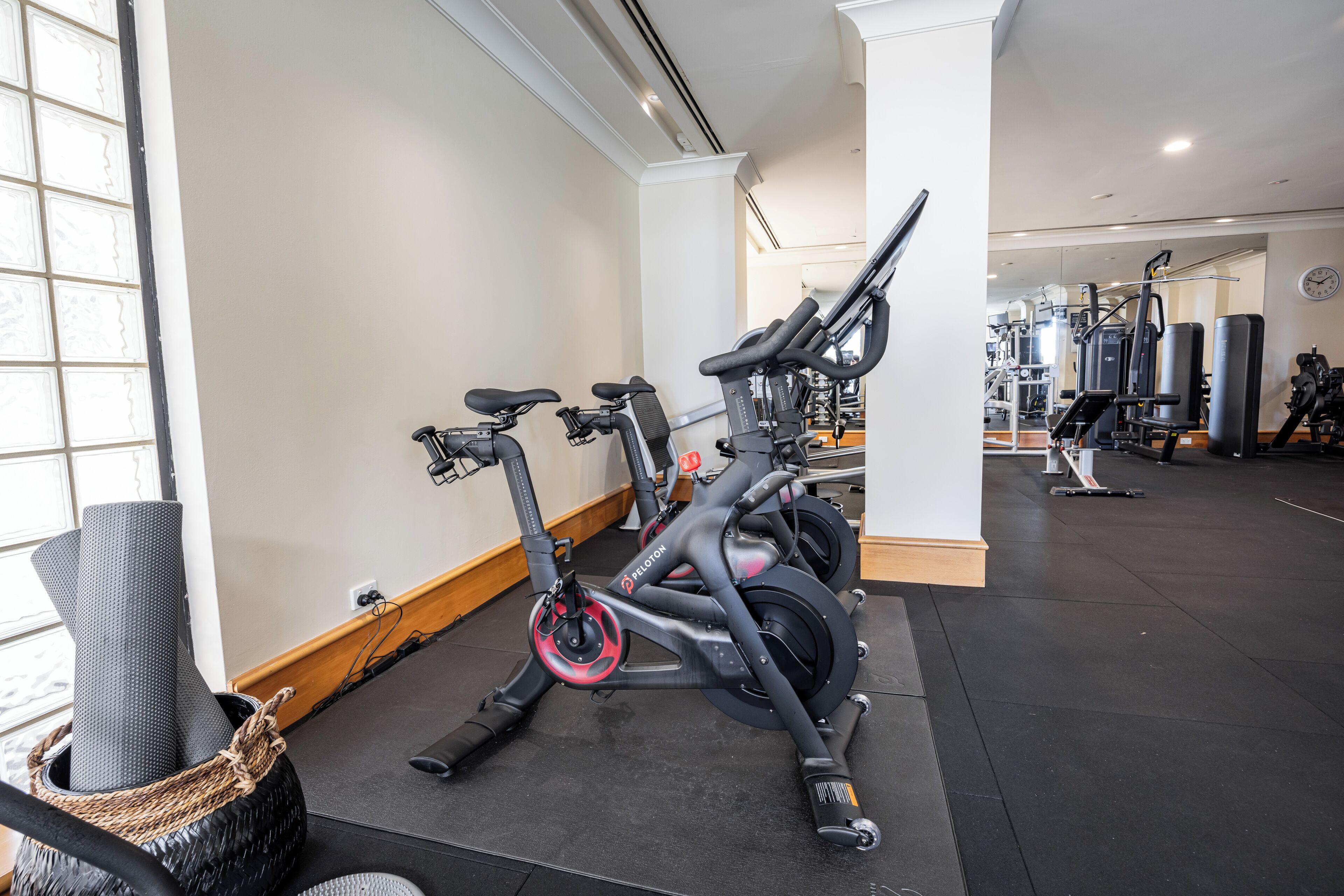 A gym with stationary bikes, weight machines, and a large mirror.