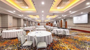 A conference room with round tables, chairs, and a projector screen displaying 'BOYDTON HOTEL EL'.