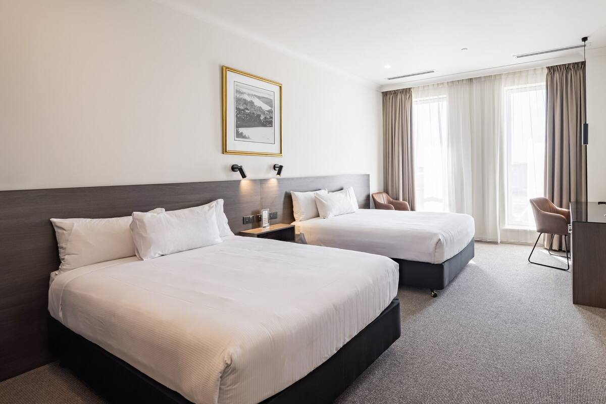 Habitació d'hotel amb dos llits, un escriptori i una cadira.
