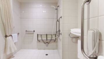 A bathroom with white tiles, a shower with a grab bar, a toilet with a hand dryer, and a towel rack.