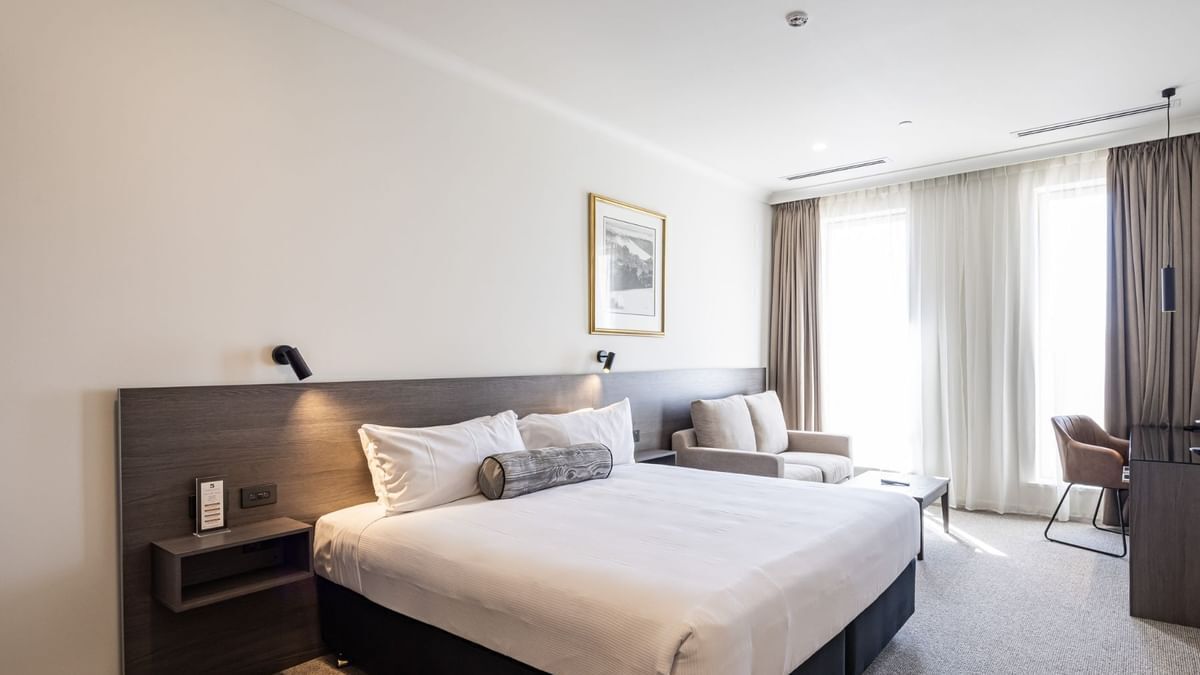 Habitación de hotel moderna con una cama grande, un escritorio, una silla y un cuadro en la pared.