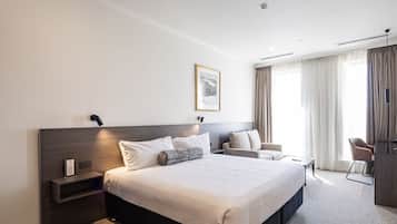 Habitación de hotel moderna con una cama grande, un escritorio, una silla y un cuadro en la pared.