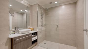 A modern bathroom with a glass-enclosed shower, a large mirror, and a vanity with a sink and storage.
