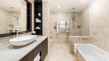 Un baño moderno con un lavamanos grande blanco, ducha con cerramiento de vidrio y bañera independiente.
