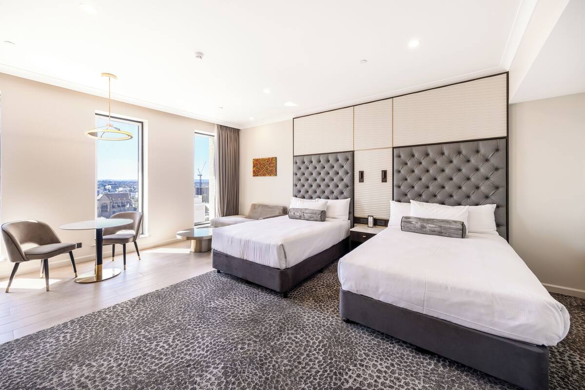 Habitació d'hotel amb dos llits, un escriptori, una cadira i vista a la ciutat.