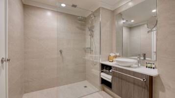A modern bathroom with a glass-enclosed shower, a sink with a mirror, and a vanity with storage.