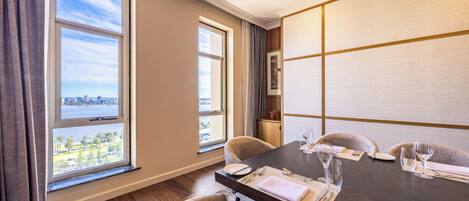 A dining area with a table set for four, large windows with a city view, and a modern interior design.