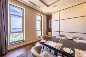A dining area with a table set for four, large windows with a city view, and a modern interior design.
