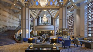 A spacious lobby with a grand chandelier, a staircase, and a seating area with sofas and armchairs.