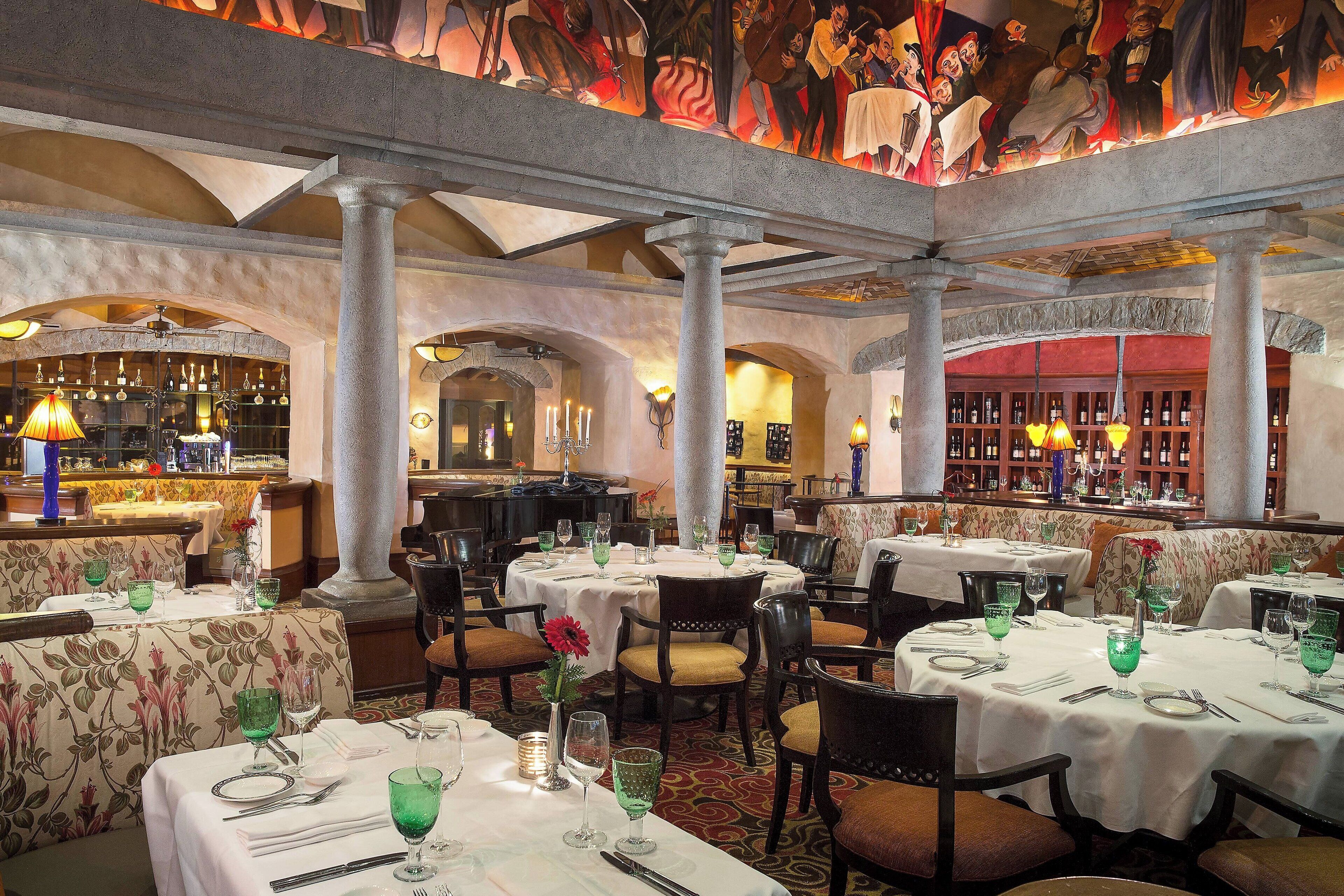 Un restaurante con mesas redondas, sillas y una zona de bar.