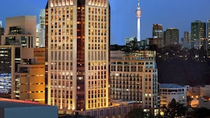 A high-rise hotel with a Sheraton sign, multiple floors, and a view of a prominent tower in the background.