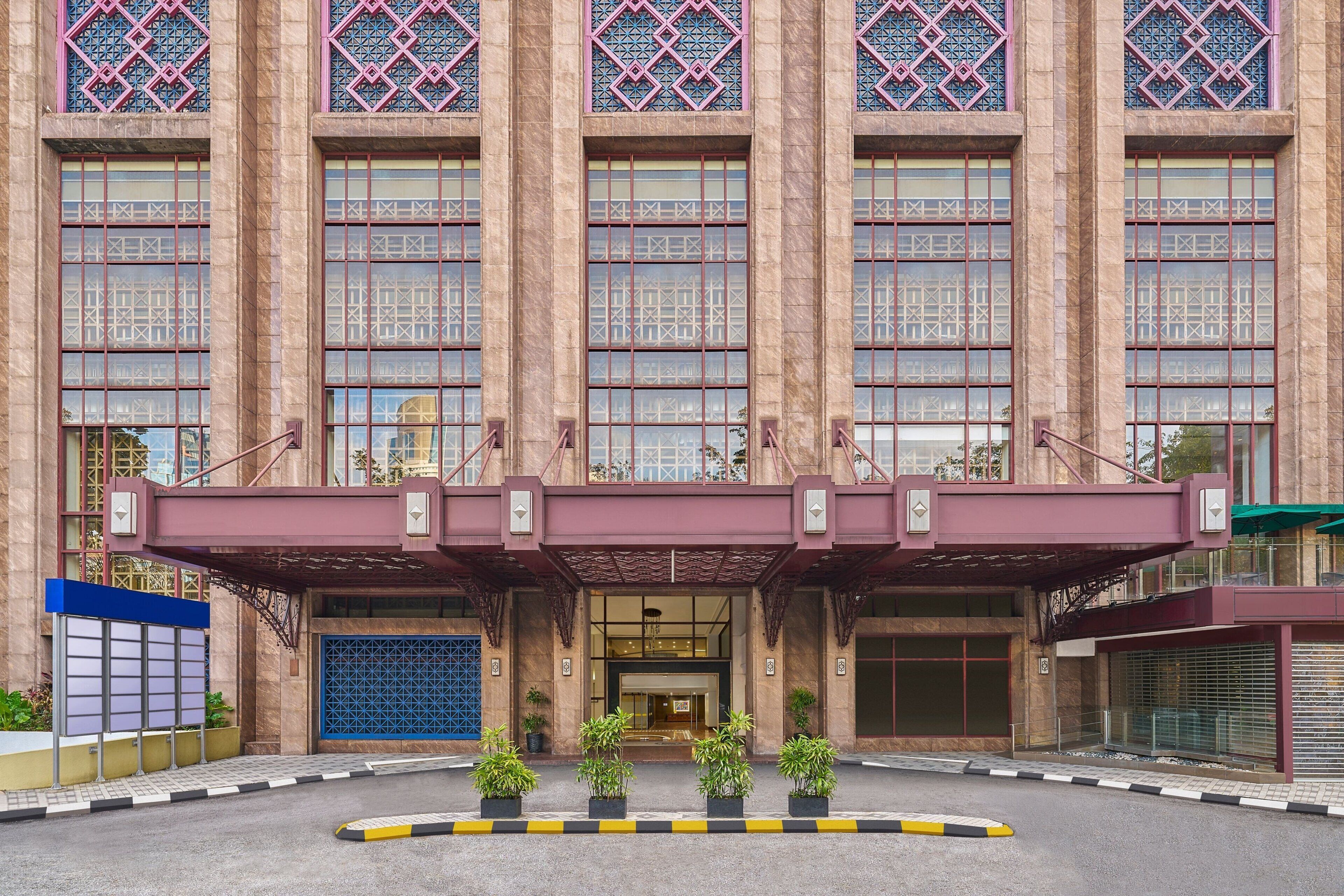 A large building with a symmetrical facade, multiple windows with intricate patterns, and a central entrance with a canopy.