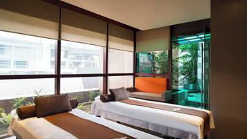 Relax in a serene space with two single beds, a cozy seating area, and a view of the surrounding greenery.